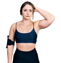 Wall Mural - Young hispanic woman wearing sportswear confuse and wonder about question. uncertain with doubt, thinking with hand on head. pensive concept.