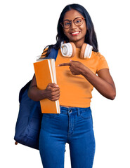 Wall Mural - Young indian girl holding student backpack and books smiling happy pointing with hand and finger