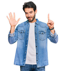 Sticker - Young hispanic man wearing casual clothes showing and pointing up with fingers number six while smiling confident and happy.