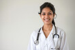 An Indian female doctor wearing a white coat and a stethoscope, with copy space