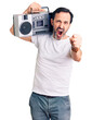 Middle age handsome man listening to music using vintage boombox annoyed and frustrated shouting with anger, yelling crazy with anger and hand raised