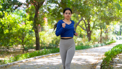 Young woman running in the park at morning, also known as jogging or morning walk