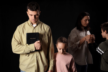 Wall Mural - Family with Holy Bible praying together on dark background
