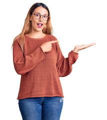 Poster - Beautiful young woman wearing casual clothes and glasses amazed and smiling to the camera while presenting with hand and pointing with finger.