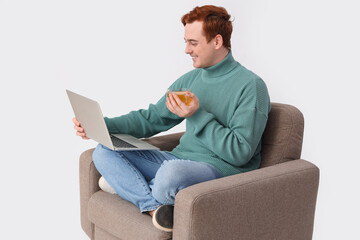 Sticker - Young man with cup of tea and laptop in armchair on white background