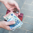 Pink purse, banknotes and coins in female hands, selective focus.	