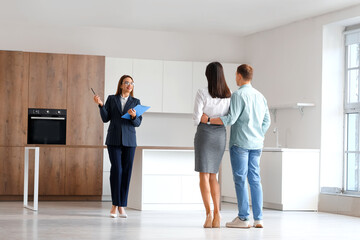 Poster - Female real estate agent with clipboard showing young couple kitchen in new house