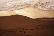 Sea foam wave and human traces on a sandy beach on a summer evening at sunset. Marine background