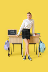 Poster - Female student near desks with chalkboard with text GOODBYE SCHOOL on yellow background. End of school concept