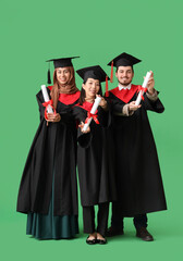 Wall Mural - Graduate students holding diplomas on green background