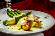 A delicious and healthy tempting dish of fresh asparagus from the asparagus farm, wrapped in bacon and potatoes, topped with a velvety cheese sauce, lunch at your favorite cafe