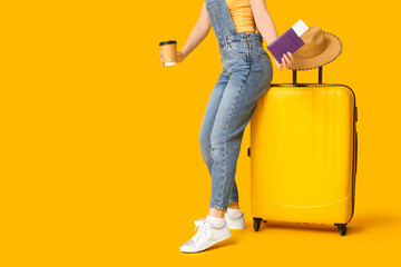 Canvas Print - Young woman with suitcase, passport and cup of coffee on yellow background. Travel concept