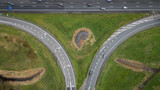 Fototapeta Miasto - 
entrance and exit on Dutch Highway road A12 at Reeuwijk near Gouda in Netherlands. Traffic flows at efficient pace with cars in lanes entering and exiting motorway. drone aerial view of transport
