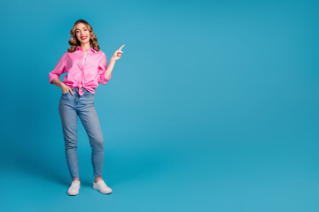 Poster - Full body photo of pretty young girl point empty space wear trendy pink outfit hairdo isolated on blue color background