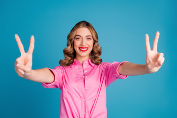 Poster - Photo portrait of pretty young girl show v-sign wear trendy pink outfit hairdo isolated on blue color background