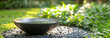   A bowl of water sits atop gravel beside a verdant park