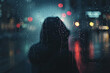 A woman is standing in the rain with her head down