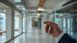 © Evgeny - Close up of businessman hand holding house key in office corridor. Real estate concept.