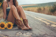 Young woman in cowboy boots sitting in middle of open road
