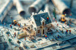 Tilt shift photo of miniature construction workers building a house from blueprints, with rolls and plans in the background. House under construction on blueprints with rolled architectural drawings.