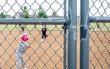 Defocused Parent view behind a chain link fence and home plate with a girl batter ready