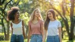 Three young women walking in the park and smiling.  Multiethnic group of friends having fun outdoors.