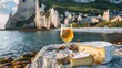 Cow cheeses of Normandy region - camembert, livarot, neufchatel, pont l'eveque and glass of apple cider drink with houses of Etretat village on background 
