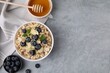 Tasty oatmeal with blueberries, mint and almond petals in bowl on grey table, flat lay. Space for text