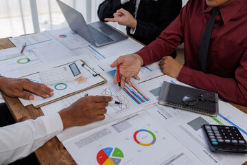 Group of confident business people point to graphs and charts to analyze market data, balance sheet, account, net profit to plan new sales strategies to increase production capacity.	