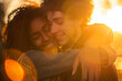 Multi ethnic young couple embracing with love with golden light sun as background