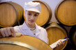 Winemaker woman checking and examining producing wine at winery in factory, inspector checking quality and fermenting wine storage in tank or barrel at room, industrial and manufacture concept.