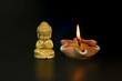 Close-up of a little Buddha statue and burning candles on a black background