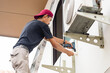 Technician man using a screwdriver to fix and install new air conditioner, repair service, and install new air conditioning concepts