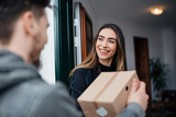 Fototapeta Natura - smiling woman receiving an elegant package from the delivery man at her front door