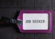 Purple office ID card on gray fabric background with text JOB SEEKER ,refers to an individual looking for employment , seeking job, unemployed person trying to get hired or change the current work