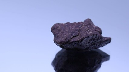 Wall Mural - meteorite stone rock sample in rotation on reflective background.