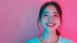 Smiling woman in pink neon light background. Cheerful Asian woman with a toothy smile enhanced by a soft pink neon backdrop giving a warm and friendly vibe
