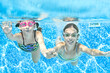 Kids swim in swimming pool underwater, little active girls have fun under water, children fitness and sport on family vacation

