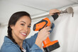 woman putting up curtain rail with a battery screwdriver