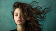 Portrait of a young woman with flowing hair on a teal background. Modern style and youth culture concept