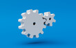 Two white cogs turning on a blue background. 3d rendering of a concept of teamwork or a good working mechanism