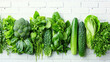 A row of vegetables including broccoli, lettuce, and cucumbers. The vegetables are arranged in a line on a white background