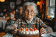 Elderly Woman Holding a Cake With Lit Candles