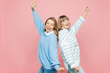 Wall Mural - Elder parent mom 50s years old with young adult daughter two women together wear blue casual clothes stand back to back spread hands dance isolated on plain pastel pink background. Family day concept.