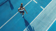 Aerial drone portrait of young woman running athlete training on an athletics track. Woman isolated against track background. Bright clear day, juxtaposition of light and shadow