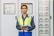 Asian male electrician engineer works standing at main circuit cabinet switchboard control water cooling pumping supply system.