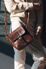 Wall Mural - beautiful woman posing with a small brown bag near grey wall