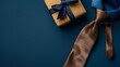 A flat lay composition featuring a stylish necktie and a wrapped gift box on a royal blue background, creating a sophisticated Father's Day ambiance.