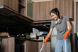 Happy young woman enjoy household chores cleaning floor in kitchen