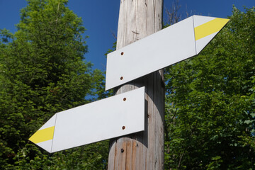 Wall Mural - Wooden signpost with two white and yellow arrows